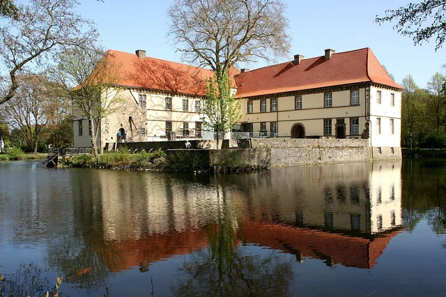 Schloss Strünkede in Herne mit roten Dächern und Spiegelung im Wasser
