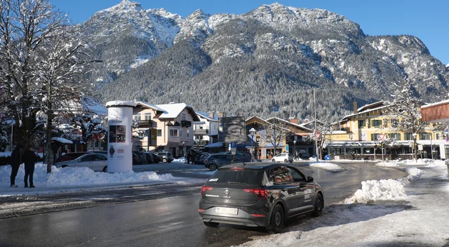 Verschneiter Marienplatz in Garmisch mit Häusern, Bäumen und den Bergen im Hintergrund