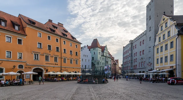 Haidplatz in Regensburg mit farbigen historischen Häusern und Straßencafés unter hellem Himmel