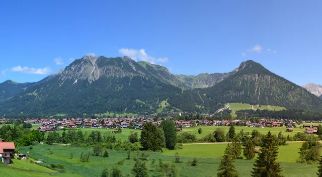 Grüne Wiesen und Wohnhäuser bei Oberstdorf vor den Allgäuer Bergen