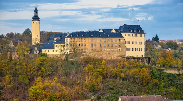 Oberes Schloss von Greiz mit Häusern und herbstlich bewaldetem Hang im Landkreis Greiz
